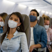 People with masks on on a plane.