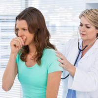 A doctor inspecting her coughing patient.
