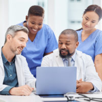 A group of doctors around a laptop.