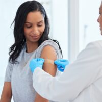 Urgent care professional putting bandaid on woman's upper arm where she got a flu shot